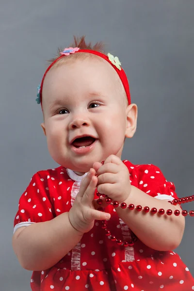 Маленька дівчинка в червоній сукні сидить біля ялинки — стокове фото