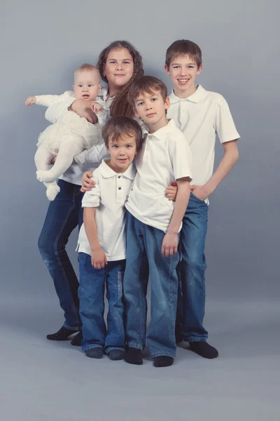 Grupo de crianças em jeans em backgroud cinza — Fotografia de Stock