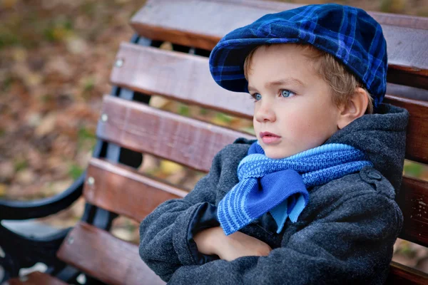 Portret van jongen op bank in park — Stockfoto