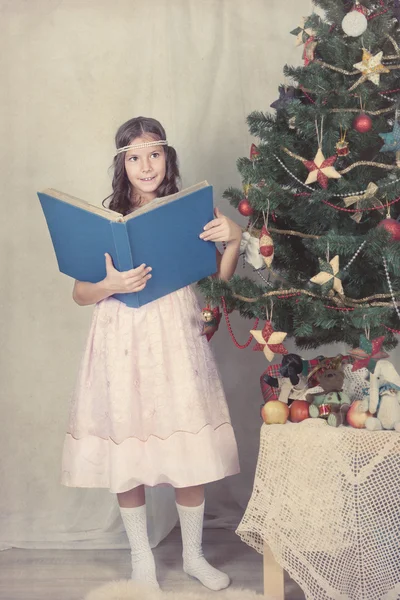 Lány könyvével, ezen a környéken: karácsonyfa — Stock Fotó