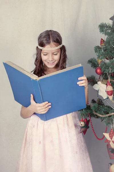 Lány könyvével, ezen a környéken: karácsonyfa — Stock Fotó