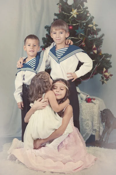 Čtyři děti sedí u vánočního stromu — Stock fotografie