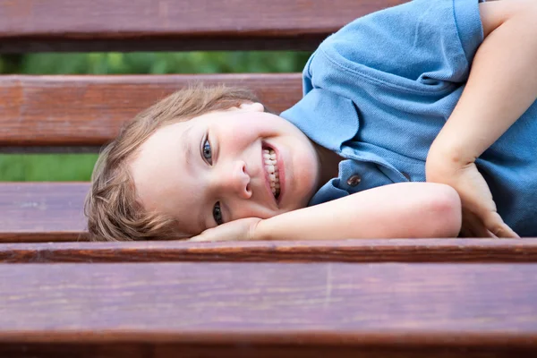 Kleiner Junge liegt auf Parkbank — Stockfoto