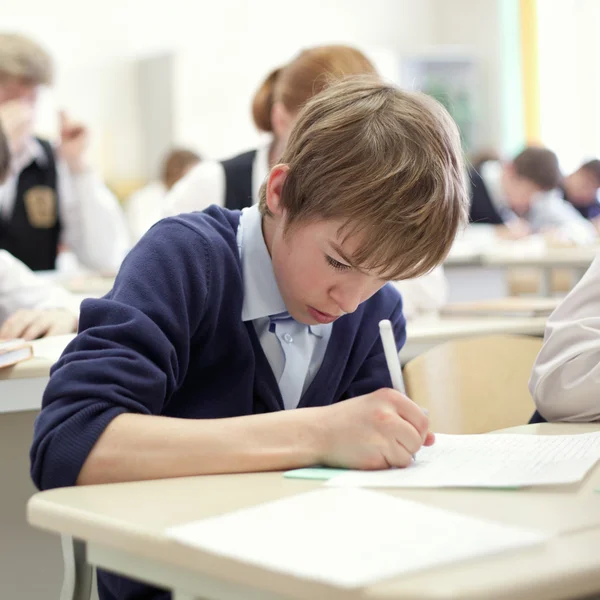 Szkole chłopiec stara się zakończyć badanie w klasie. — Zdjęcie stockowe