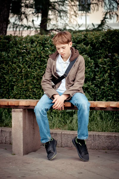 Triste adolescente sentado no banco no parque — Fotografia de Stock