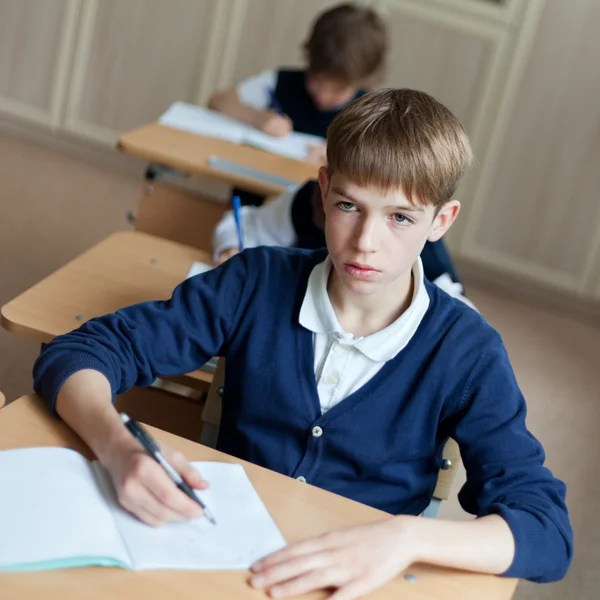 Pilný student sedí u stolu, učebny — Stock fotografie