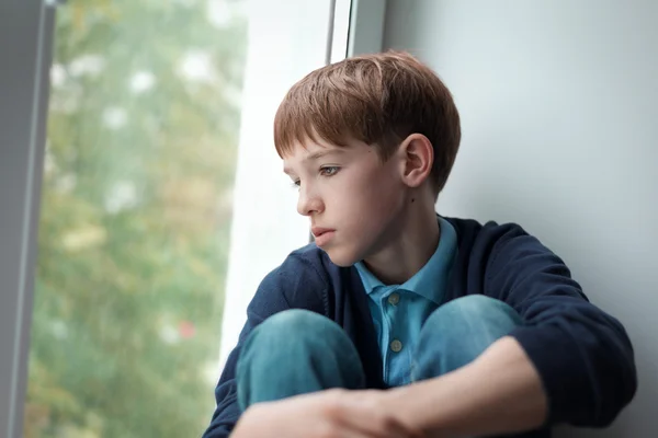 Adolescente triste sentado na janela — Fotografia de Stock