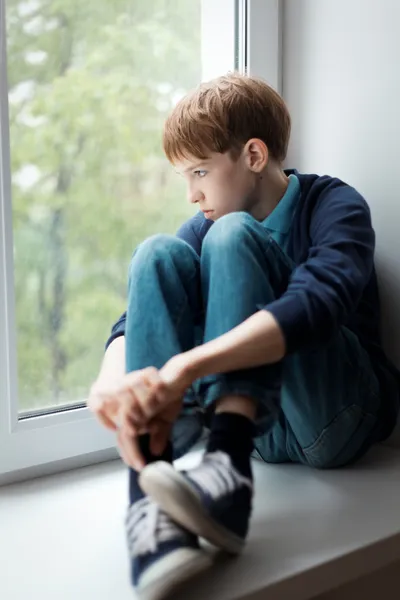 Triste adolescente sentado en la ventana — Foto de Stock