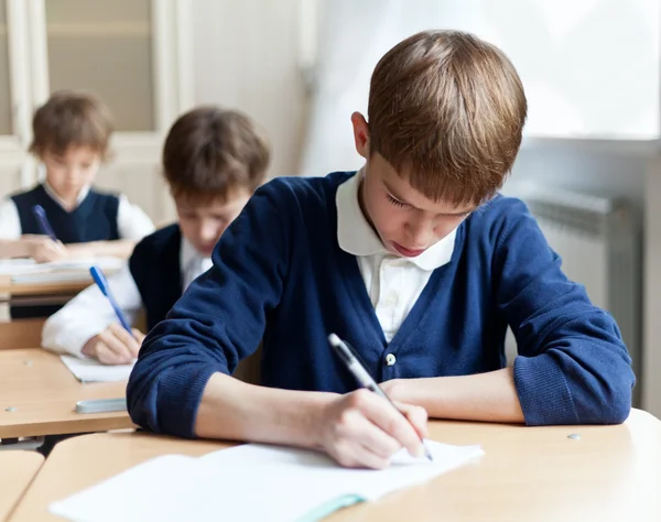 Fleißiger Schüler sitzt am Schreibtisch, Klassenzimmer — Stockfoto