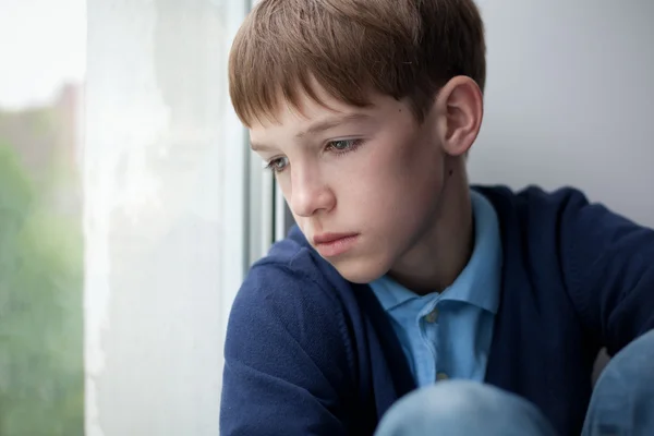 Adolescente triste sentado na janela — Fotografia de Stock