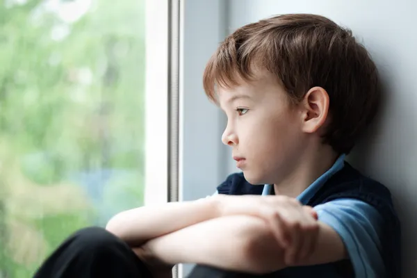 Triste garçon assis sur la fenêtre — Photo