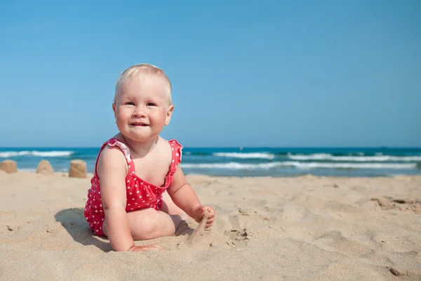 Kum plajı üzerinde oturan küçük kız — Stok fotoğraf