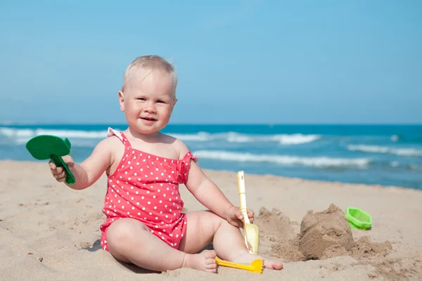 Pieni tyttö istuu hiekalla rannalla — kuvapankkivalokuva