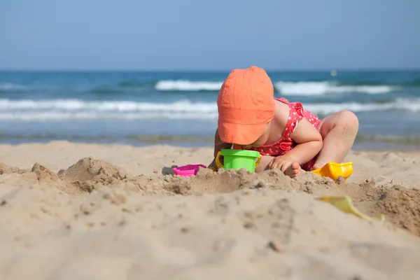 Little girl sitting on sand at beach — Stock Photo, Image