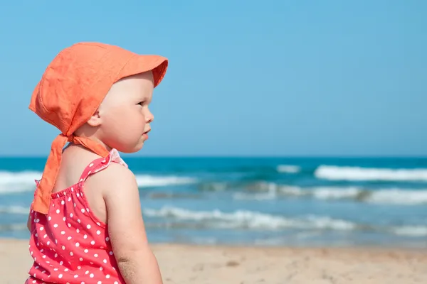 Niña sentada en la arena en la playa — Foto de Stock