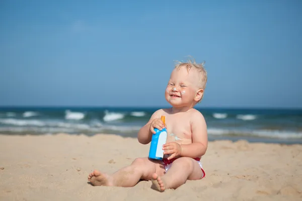 Menina adorável na praia aplicando creme protetor solar Fotografias De Stock Royalty-Free