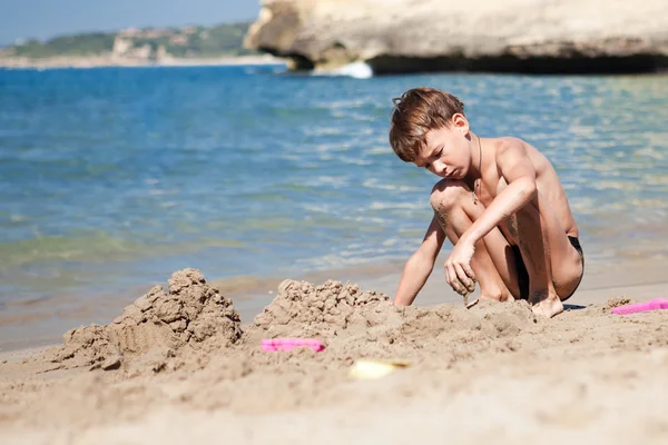 Niño haciendo castillo de arena en la playa — Foto de Stock