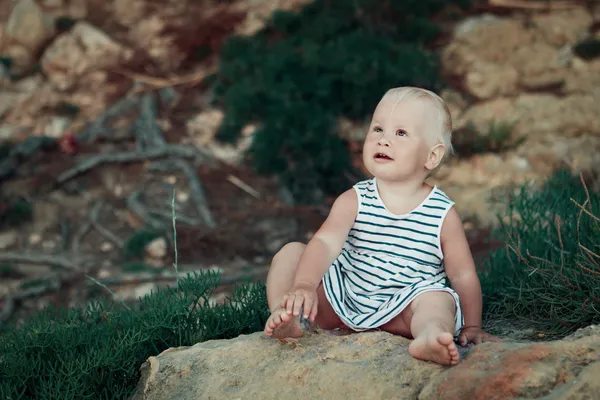 Kleines Mädchen sitzt auf einem Felsen, im Freien — Stockfoto