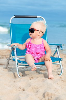 plaj sandalye üzerinde oturan mutlu küçük kız