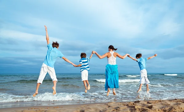 Mother and three sons are jumping on beach — Stock Photo, Image