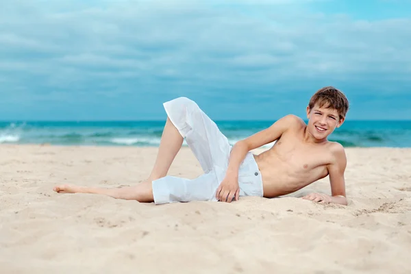 Ritratto di adolescente sdraiato sulla sabbia vicino al mare — Foto Stock
