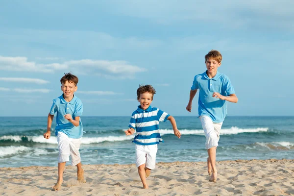 Tres hermanos corren en la playa — Foto de Stock