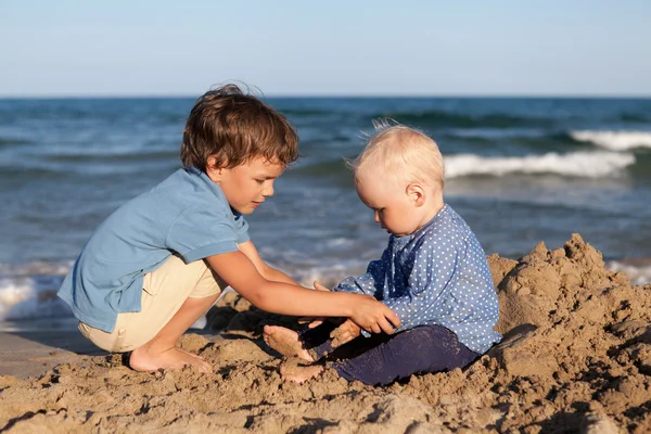 Irmão e irmã brincando na areia na praia — Fotografia de Stock