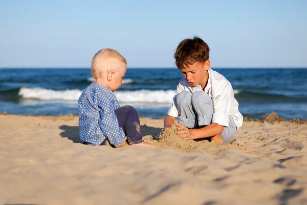 Irmão e irmã brincando na areia na praia — Fotografia de Stock