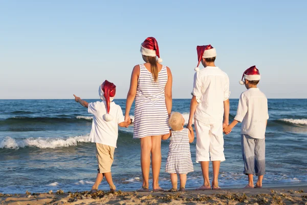 Niños en el sombrero de Santa Claus están de pie en la playa — Foto de Stock