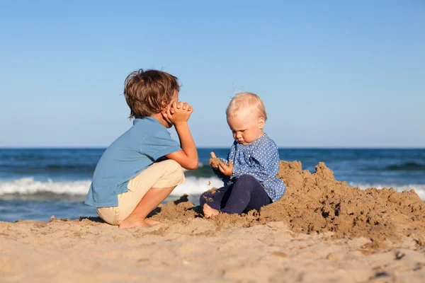 Frère et sœur jouant dans le sable à la plage — Photo