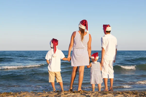 Children in santa claus hat are standing on beach — Stock Photo, Image