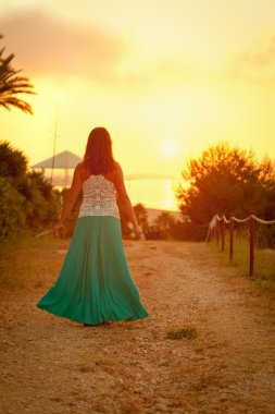 gün batımında kumsal boyunca yürüyen güzel bir kız