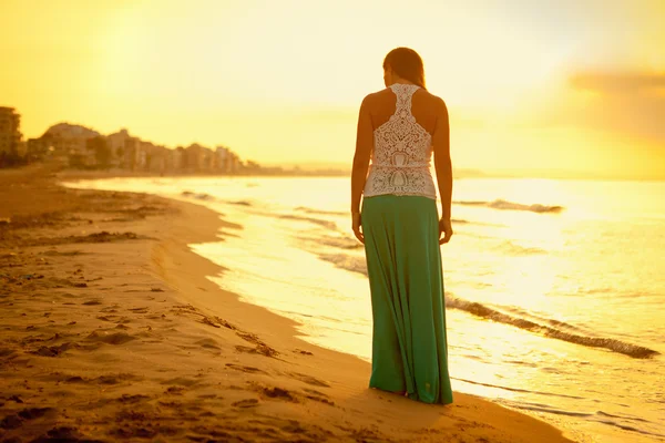 Gün batımında kumsal boyunca yürüyen güzel bir kız — Stok fotoğraf
