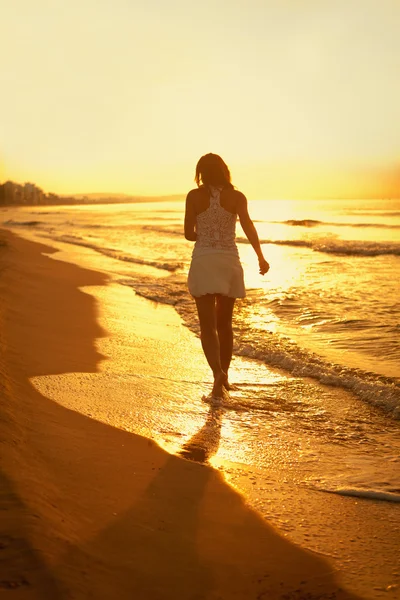 Schönes Mädchen, das am Strand bei Sonnenuntergang spaziert — Stockfoto