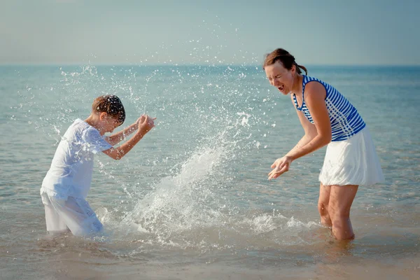 Mamma e figlio spruzzi d'acqua in mare — Foto Stock