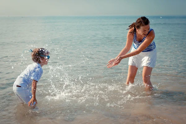 Мама и сын брызгают водой в море — стоковое фото