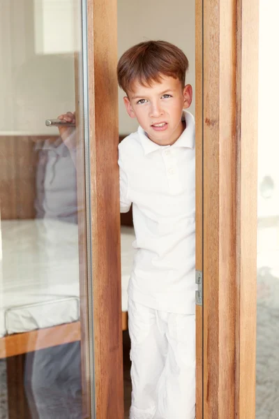Surprised boy peeks from behind door — Stock Photo, Image