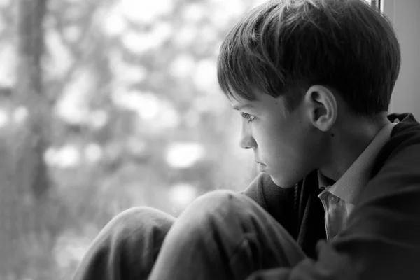 Triste adolescente sentado en la ventana — Foto de Stock