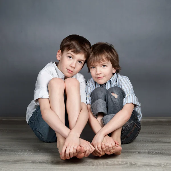 Retrato de dois irmãos felizes no fundo agray — Fotografia de Stock
