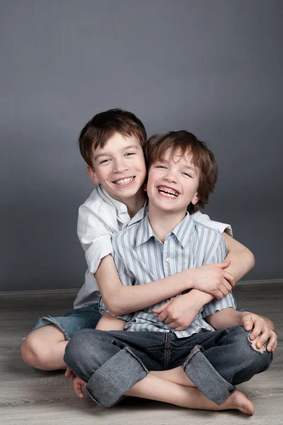 Portrait de deux frères heureux sur fond agray — Photo