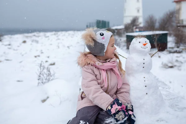 Menina Abraça Boneco Neve Passeio Inverno Praia Perto Farol Livre — Fotografia de Stock