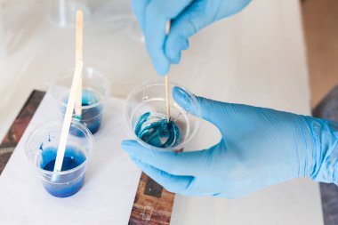 Yaratıcılık için iki reçine bileşeni karıştırma işlemi, eldivenli eller, reçine sanatı ustası sınıfı