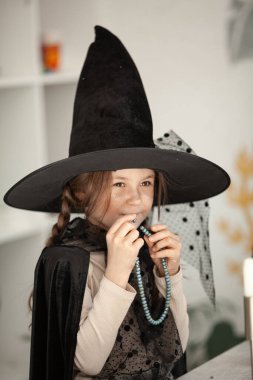 Cadı kostümlü bir kızın portresi, çocuğun kafasında siyah bir şapka, Cadılar Bayramı partisi.