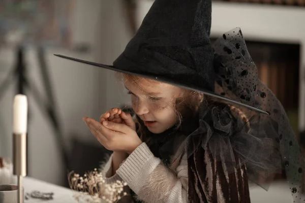 戴着女巫帽的女孩会变出蜡烛 孩子们会穿上万圣节派对的服装 打扮得很漂亮 — 图库照片