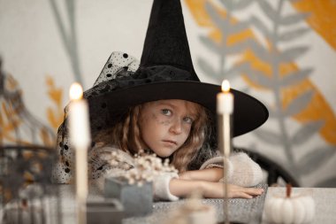 Cadı kostümlü bir kızın portresi, çocuğun kafasında siyah bir şapka, Cadılar Bayramı partisi.