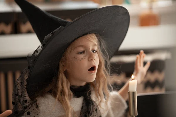 魔女の帽子の女の子はキャンドルを呼び起こし 子供はハロウィンパーティーの衣装を着て 美しい装飾 — ストック写真