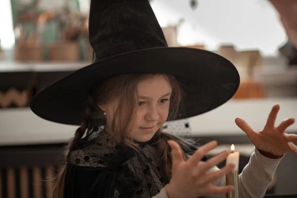 魔女の帽子の女の子はキャンドルを呼び起こし 子供はハロウィンパーティーの衣装を着て 美しい装飾 — ストック写真