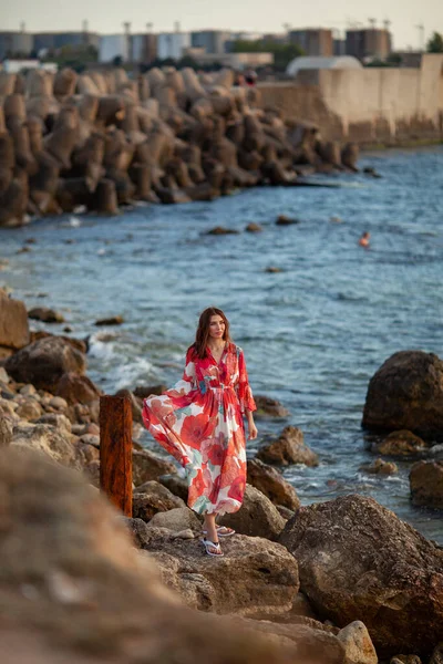 美丽的女人穿着红色长裙在防波堤边 在海边散步 — 图库照片
