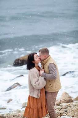 Birbirlerine aşık güzel bir çift kış denizi kıyısında yürüyor.