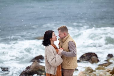 Birbirlerine aşık güzel bir çift kış denizi kıyısında yürüyor.